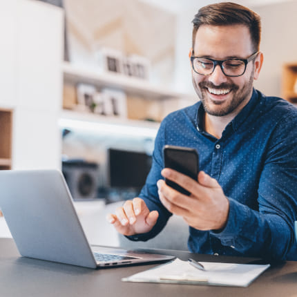 A smiling man looking at his smartphone representing digital marketing agency social media services